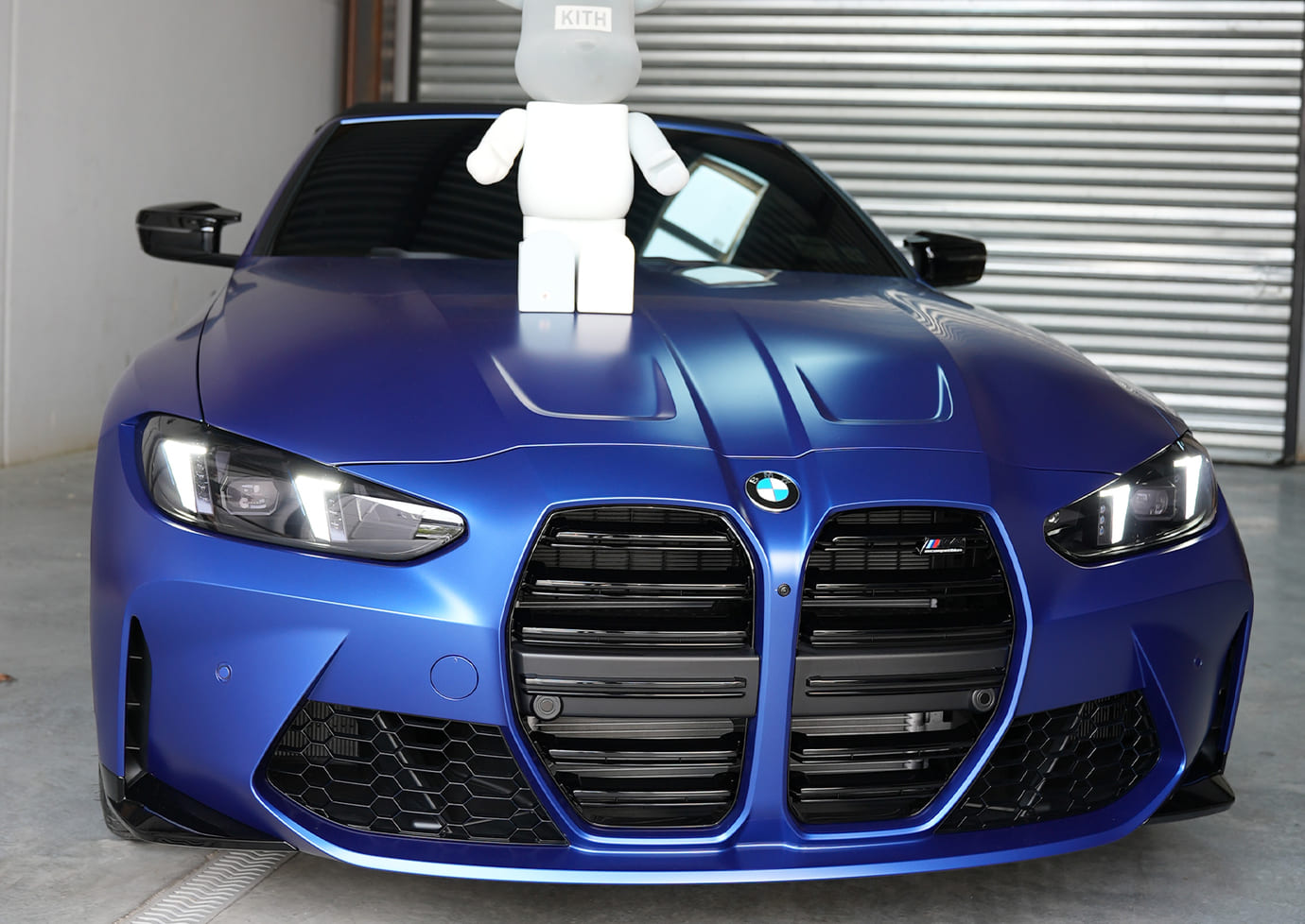 Sleek blue sedan with ceramic coating gleaming under sunlight on a Brooklyn city street, showcasing superior shine and paint protection in an urban environment