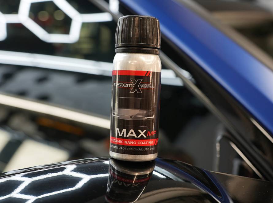 Modern car driving through Brooklyn with System X Ceramic Coating, reflecting sunlight and street scenery on flawless paintwork