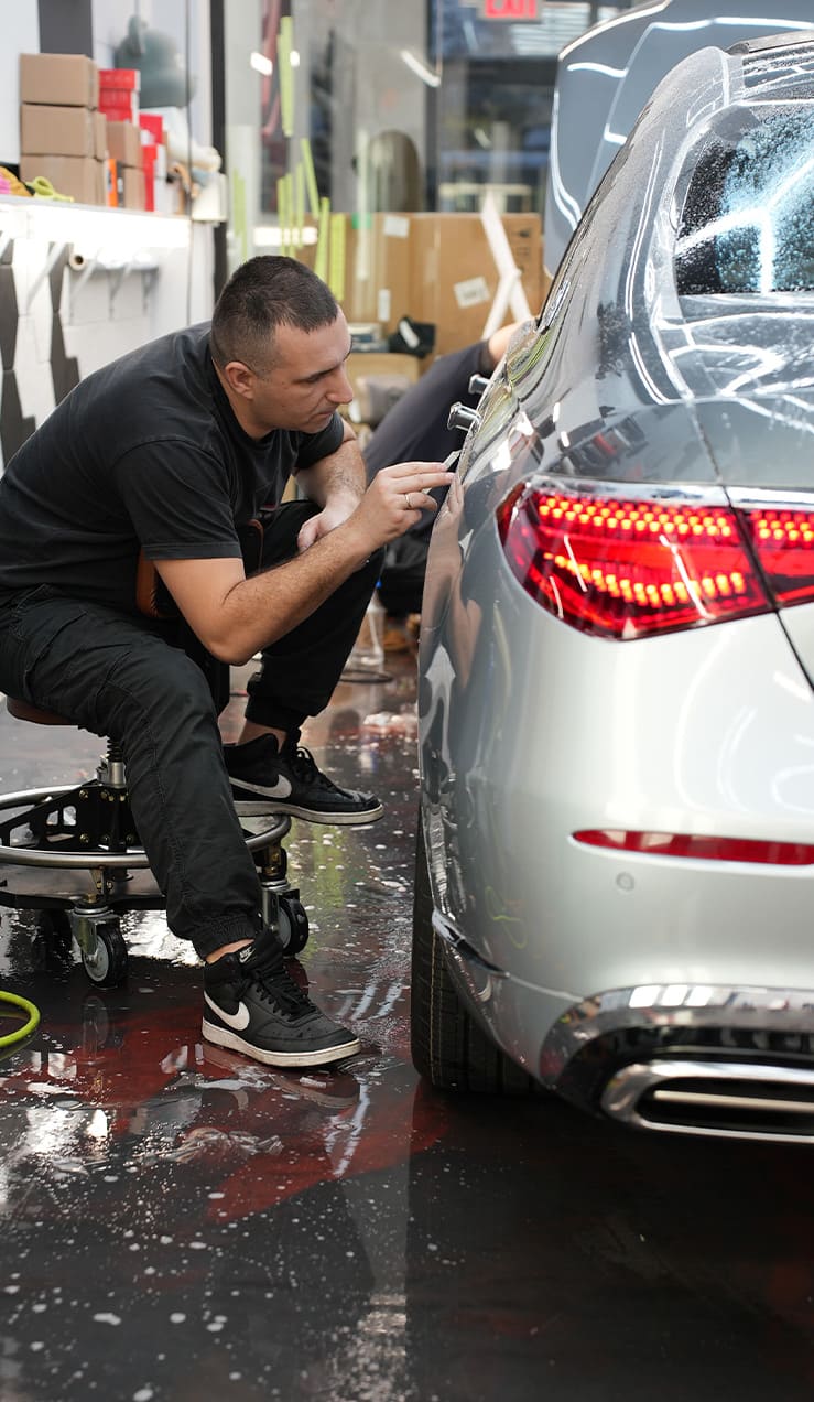 STEK PPF Installation in Brooklyn by Grand Prix Customs Professional installer applying STEK Paint Protection Film on car hood at Grand Prix Customs Brooklyn NYC